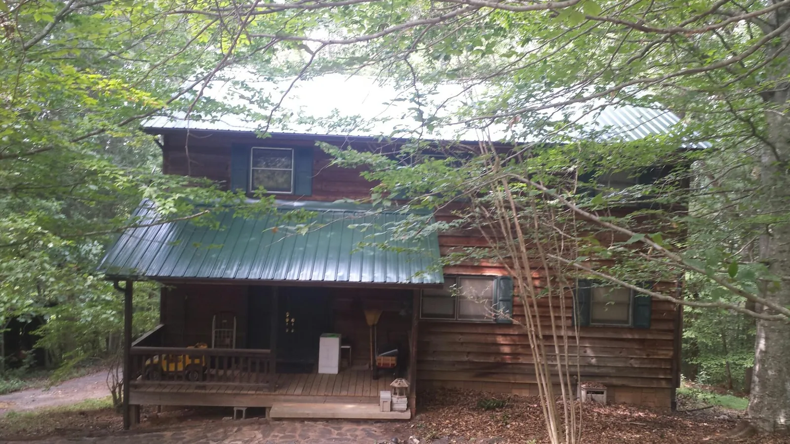Green metal roof and covered porch on a log cabin in Meredith