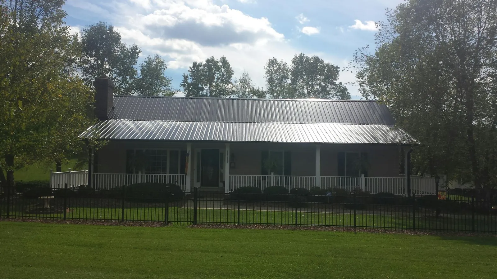 Gray metal roof on a brick ranch with a full width front porch — Gutter Guard Installation work by our crew in Meredith