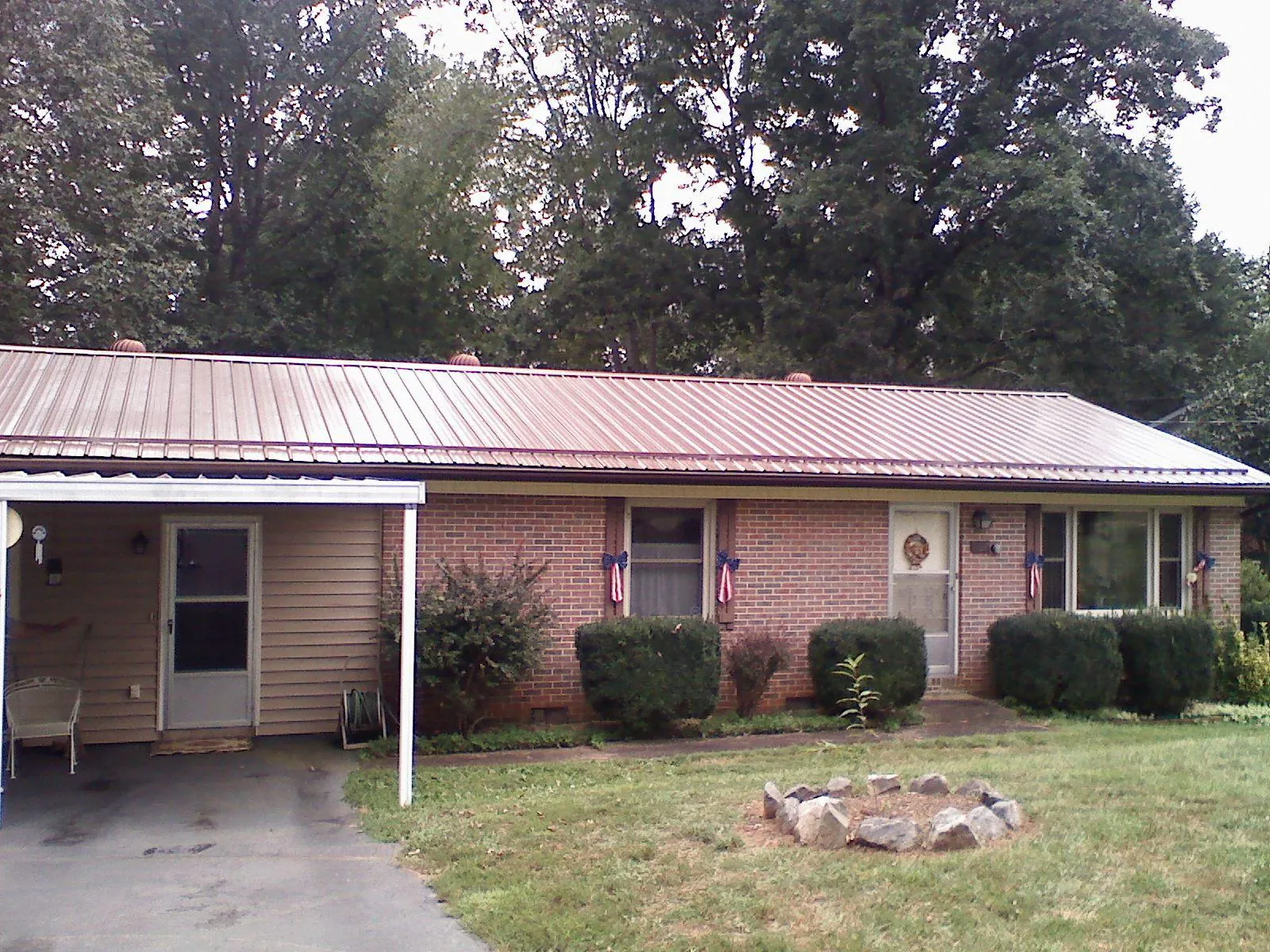 Bronze metal roof and carport on a brick ranch home — Roof Repair work by our crew in Meredith